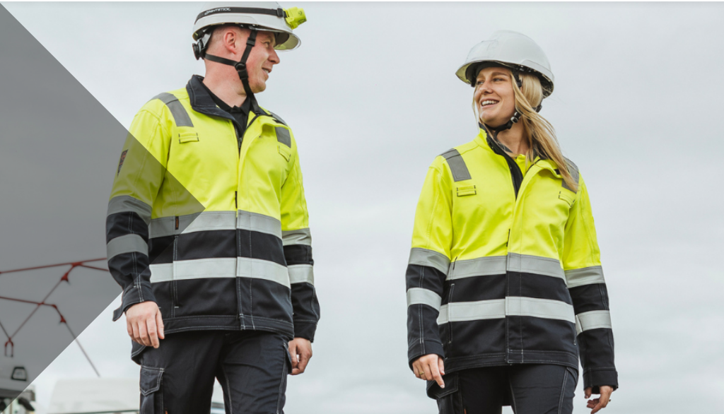 Two workers in high-visibility safety jackets and hard hats at an industrial site